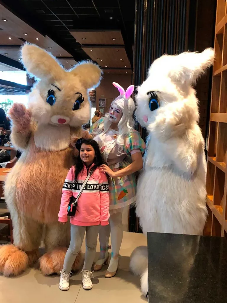 coelhete e coelhos da páscoa posando para foto junto com criança