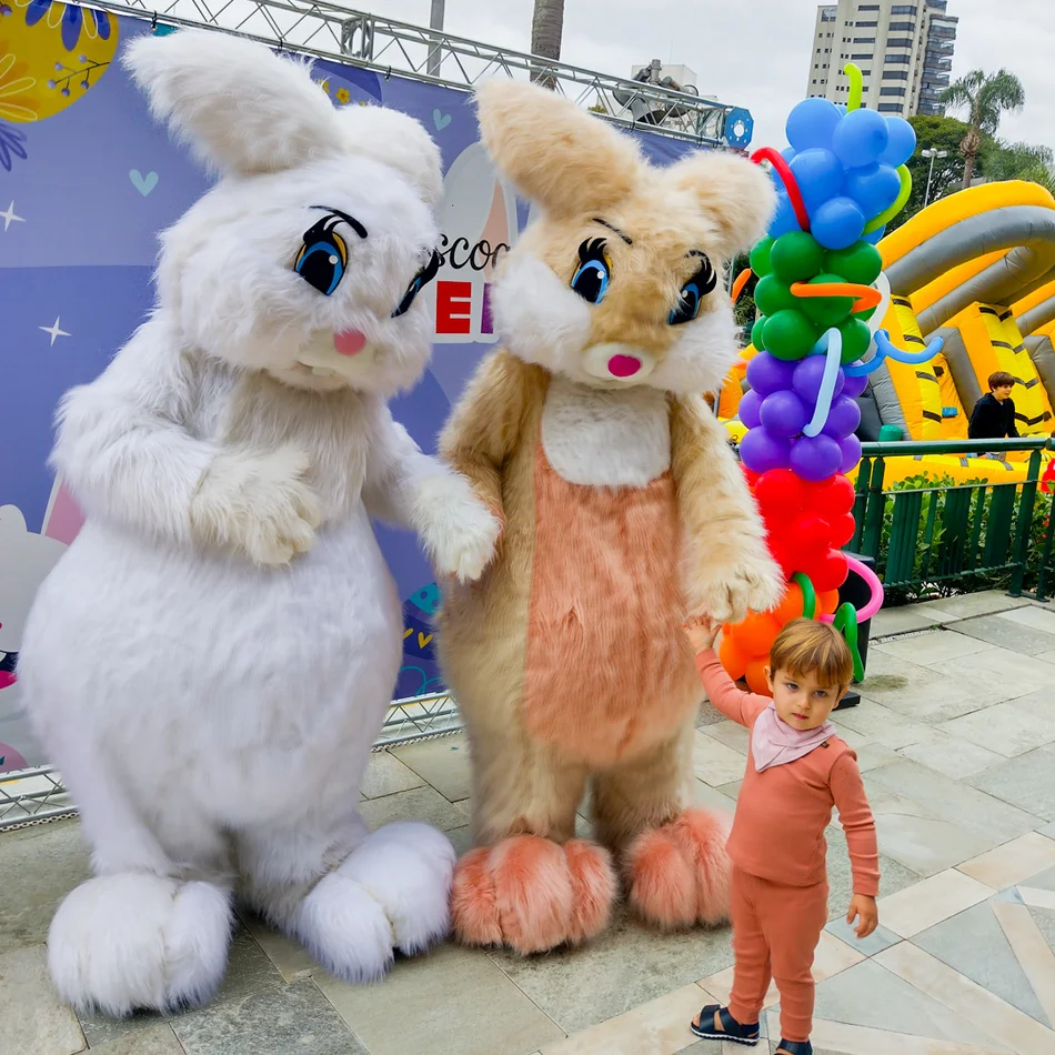 Personagem Coelho da Páscoa laranja participando de caça aos ovos em festa infantil